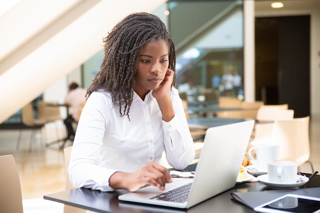 Focused young female office worker working in coffee shop