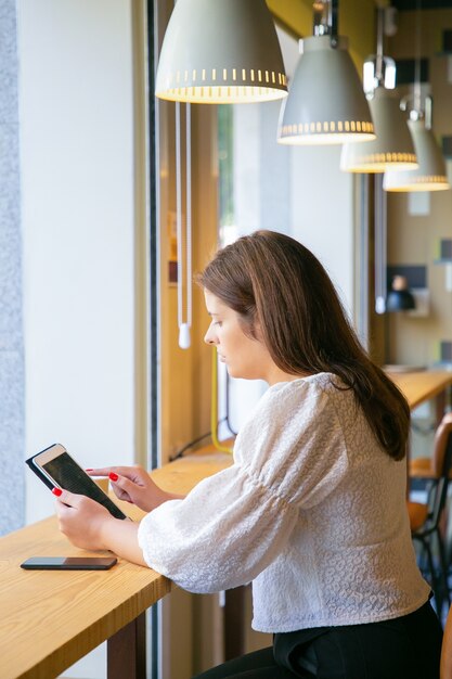 Focused young female professional using tablet while sitting at desk in co-working space