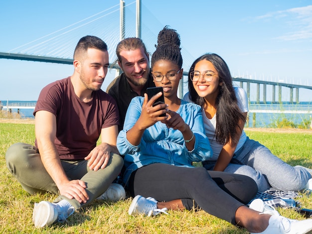 Ориентированные молодые друзья с помощью смартфона на открытом воздухе
