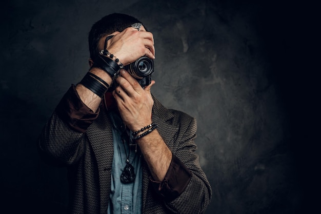 Focused young photographer is taking a photo on the dark grunge background.