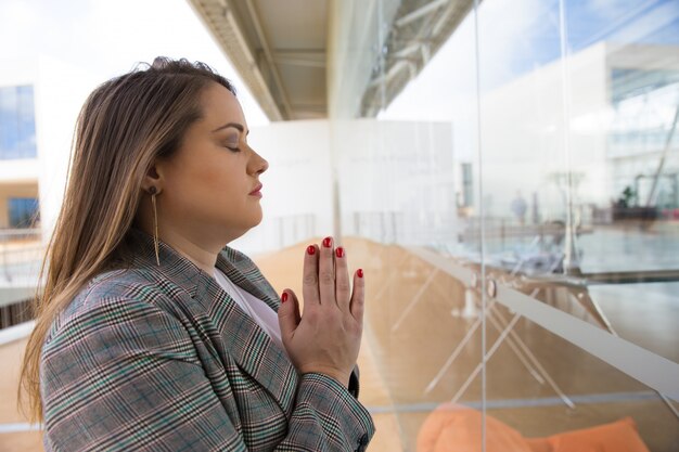 Focused young woman praying with closed eyes