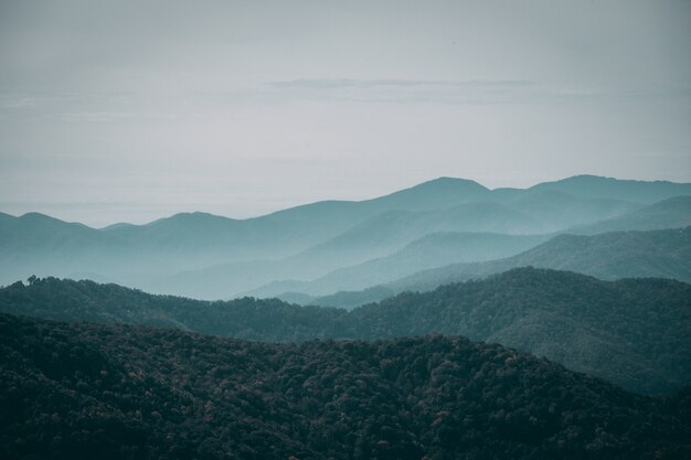 薄暗い空の下の霧深い山岳風景