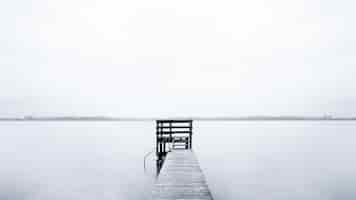 Free photo foggy scenery of a pier leading to the ocean on a cold morning