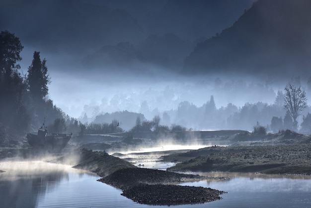 Foggy shore of a lake with forests at night