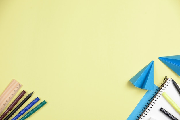 Folded blue papers with office stationeries against yellow backdrop with space for writing the text