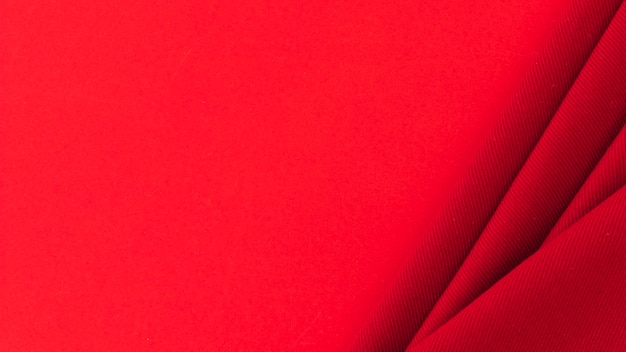 Free photo folded red textile fabric on colored background