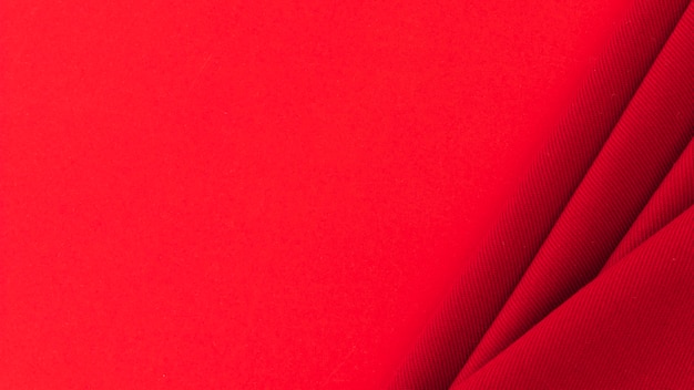 Free Photo folded red textile fabric on colored background
