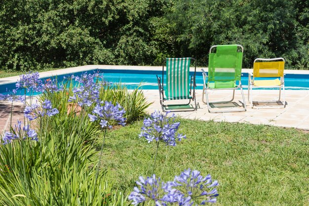 Folding chairs near pool and lawn in yard