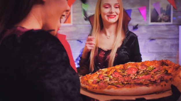 Follow shot of witch girl arriving with pizza at halloween party.