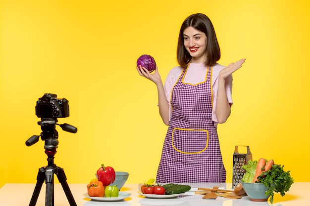 Food blogger cute lovely girl in pink apron recording video for social media happy with veggies