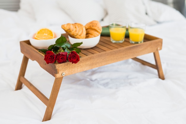 Food and blooms on breakfast table on bed