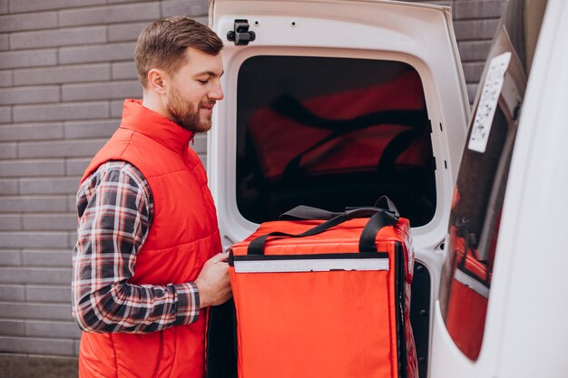 Food delivery man putting food box into a car