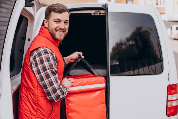 Food delivery man putting food box into a car