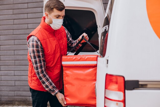 Food delivery man putting food box into a car