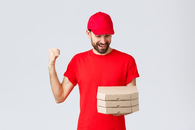 Food delivery quarantine stay home and order online concept happy excited bearded courier in red tsh...