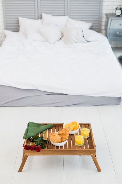 Food and flowers on breakfast table near bed