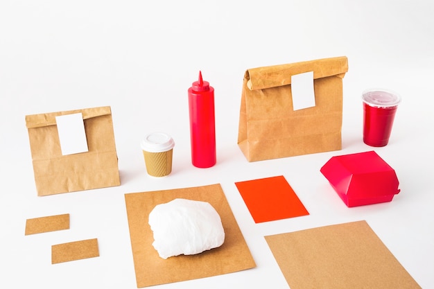 Food packages with disposal cup and sauce bottle on white background