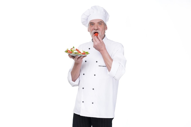 Food service, organic food, healthy diet, cooking and professional culinary concept, elderly chef in white uniform holds vegetable salad.