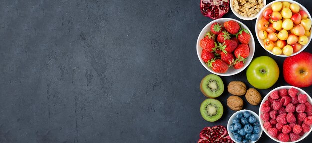 Еда с высоким содержанием антиоксидантов: ягоды, орехи, фрукты. черный бетонный фон. скопируйте пространство.