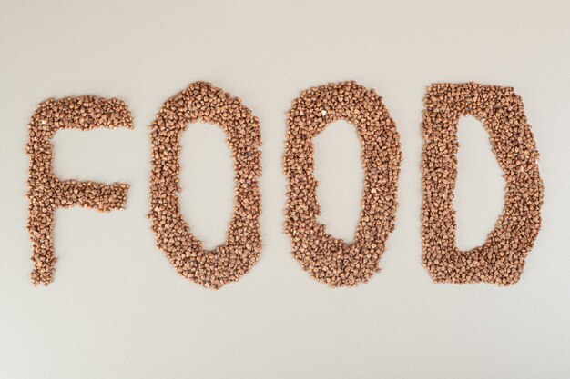 Food writing with brown beans on concrete.