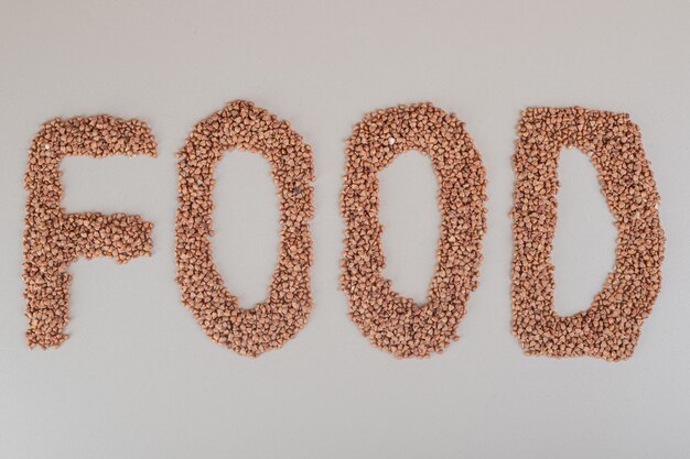 Food writing with brown beans on concrete.