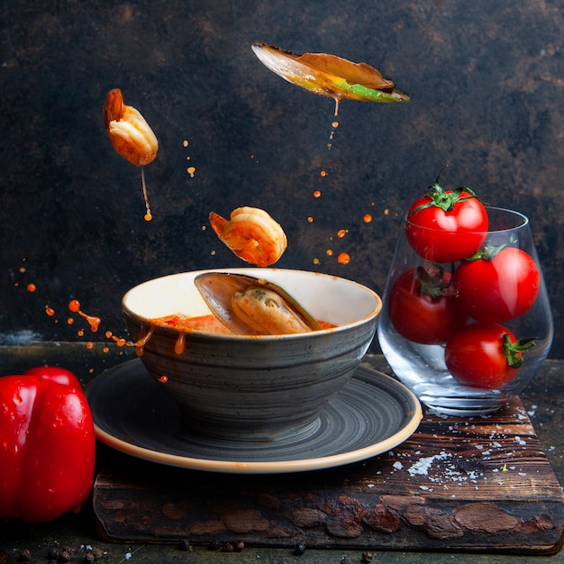 Foods flying in the air with tomatoes on black textured background side view