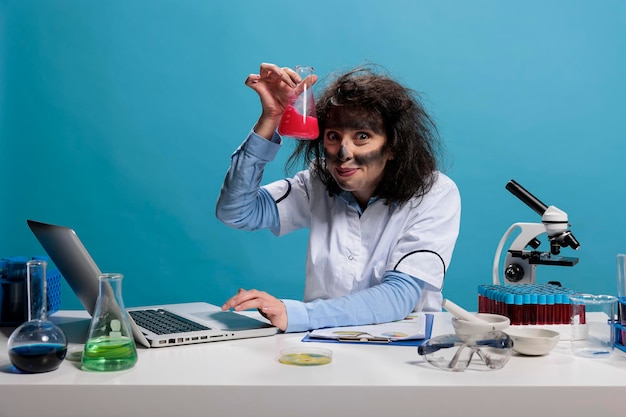 Free photo foolish funny looking crazy chemist having glass flask filled with experimental liquid serum after failed chemical experiment. mad silly lab worker having wild look and weird face expression.