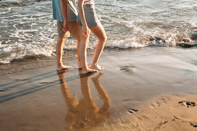 ビーチで歩くカップルの足の景色