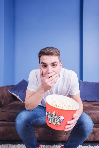 Free photo football fan on couch with popcorn