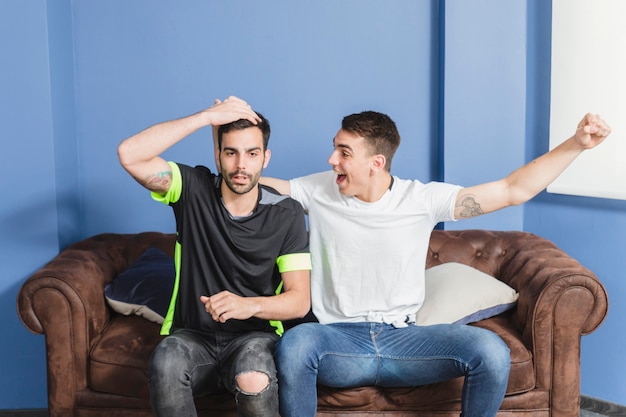 Free photo football fans celebrating in living room