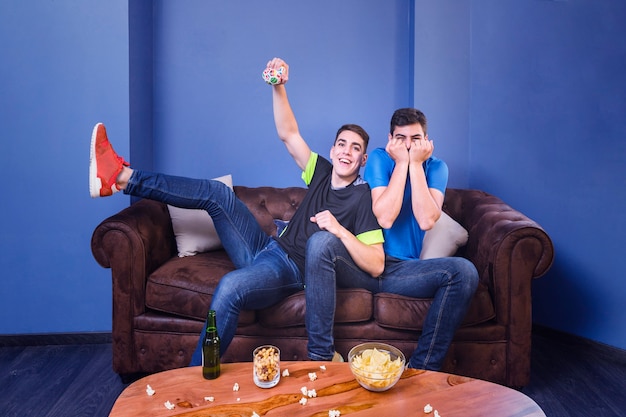 Football fans celebrating with popcorn on table