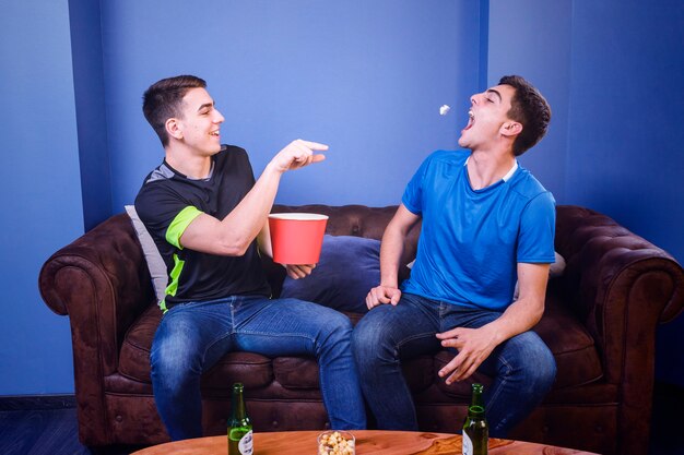 Football fans on couch with popcorn