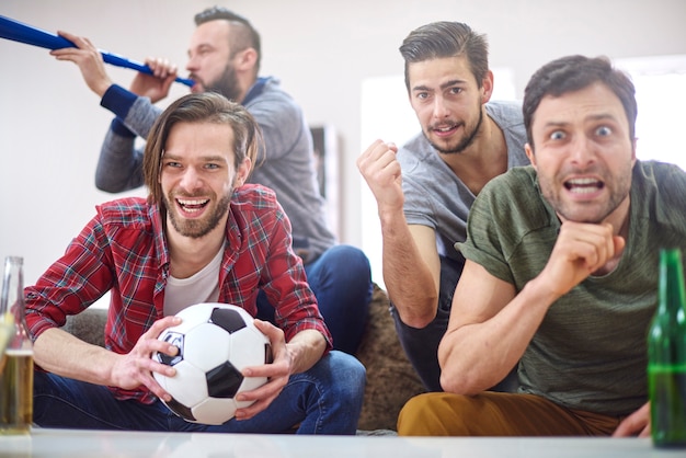 Free photo football fans watching match at home