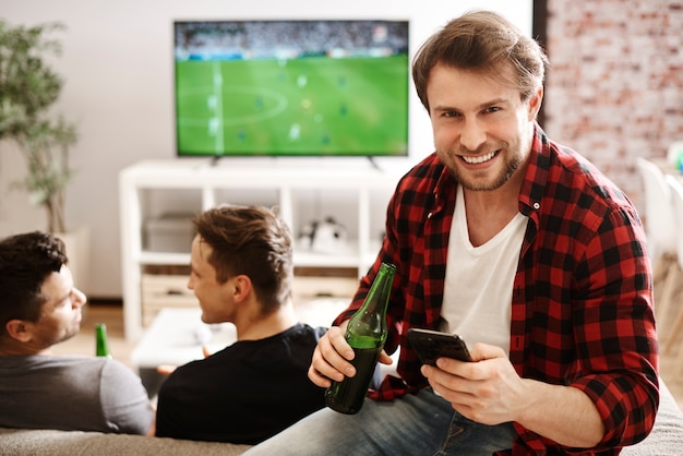 Football fans with mobile phone and beer