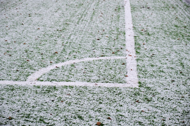 Football field, lawn under snow, first snow on grass, football field markings