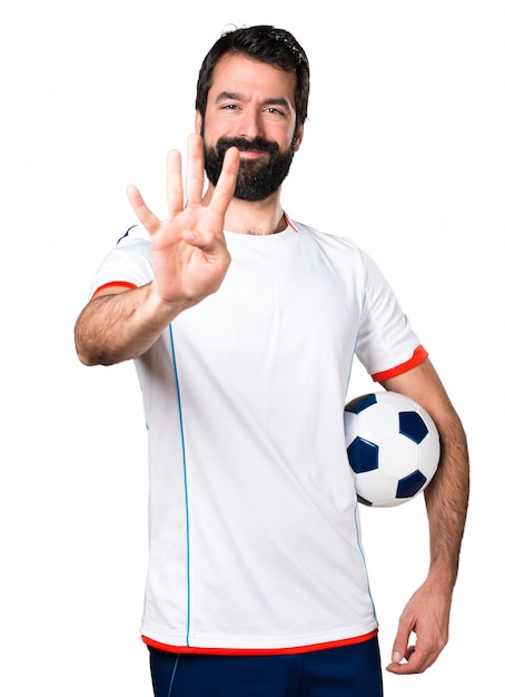 Football player holding a soccer ball counting four