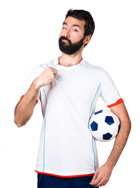 Free photo football player holding a soccer ball proud of himself