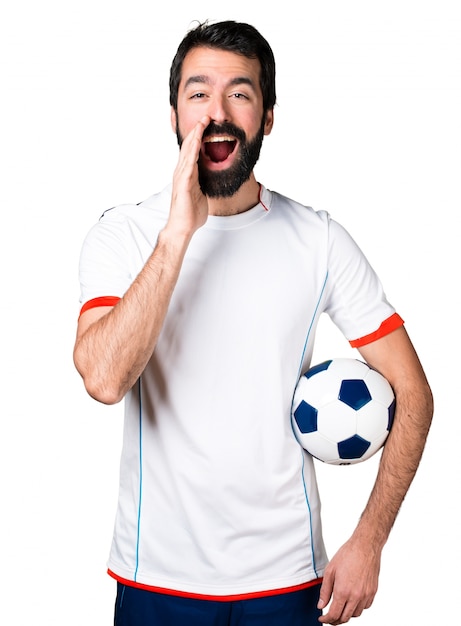 Free photo football player holding a soccer ball shouting