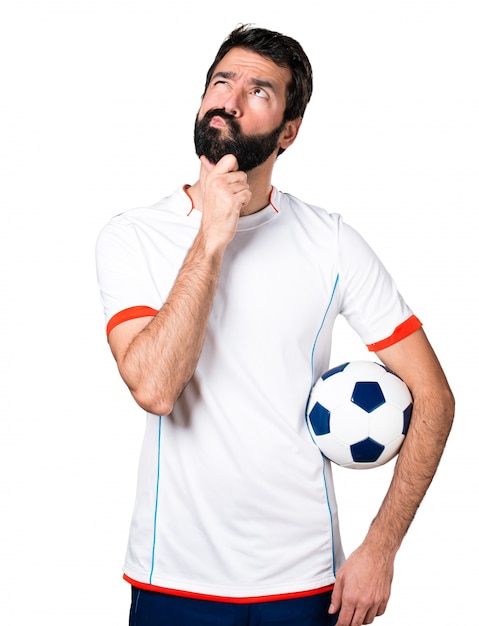 Football player holding a soccer ball thinking