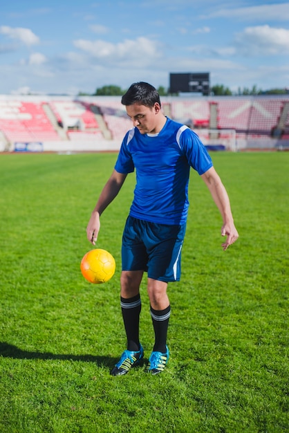 Football player juggling ball in stadium
