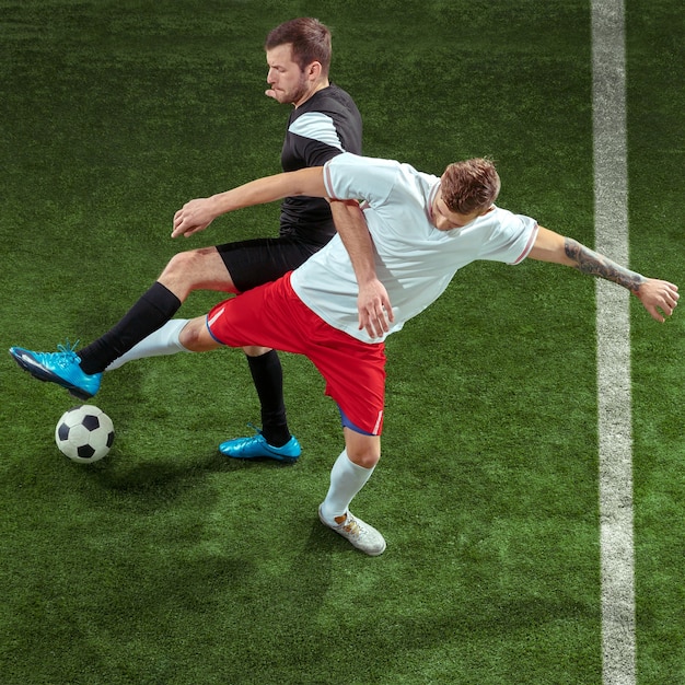 Football player tackling for ball over green grass background.