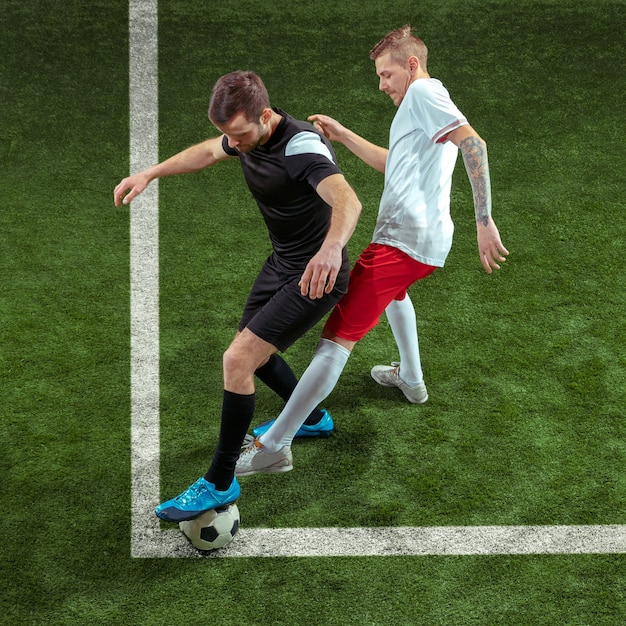 Football player tackling for ball over green grass background.