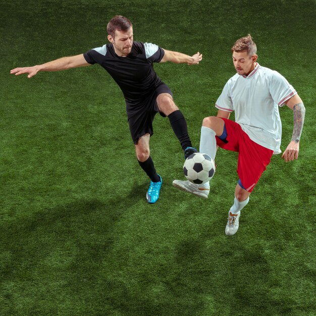 Футболист решает мяч над зеленой травой