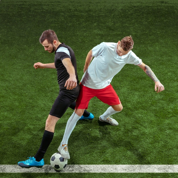 Football player tackling for ball over green grass