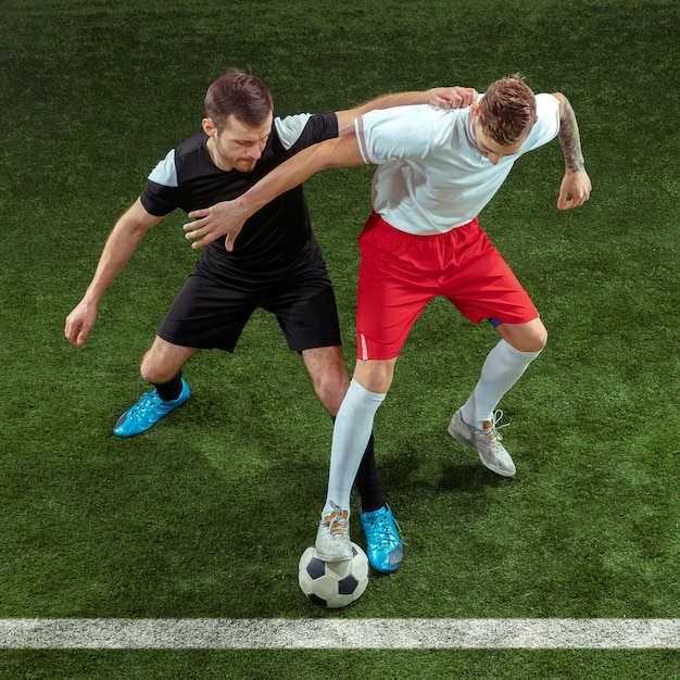 Football player tackling for ball over green grass