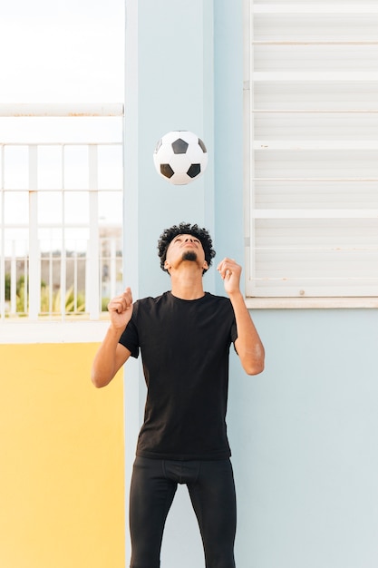 Бесплатное фото Футболист бросает мяч на крыльце