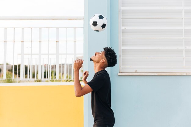 Football player throwing up ball at porch