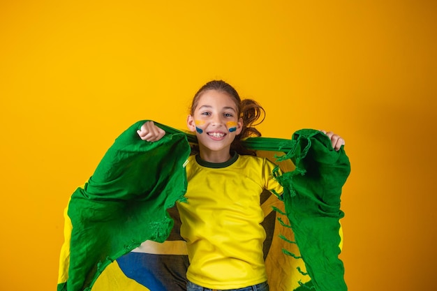 Football supporter, brazil team. beautiful little girl cheering for her team on yellow background
