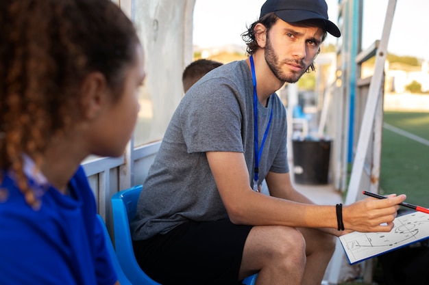 Football trainer teaching kids  side view