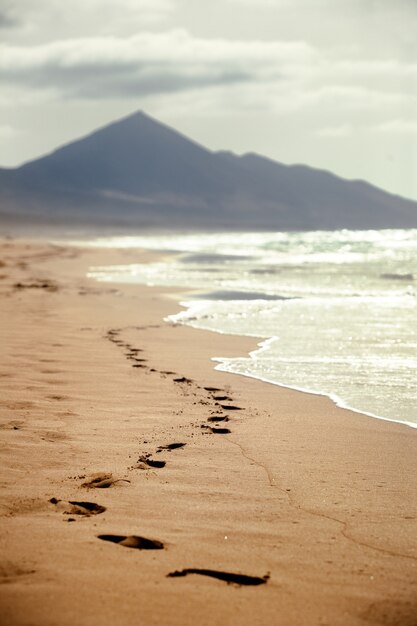 Footprints on a sandy beach with a mountain in background in the Canary Islands, Spain